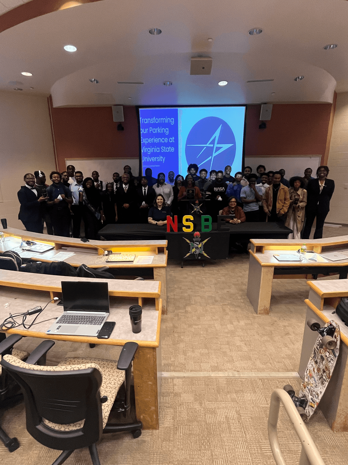 Group photo in a lecture hall with a projector displaying a presentation at Virginia State University.